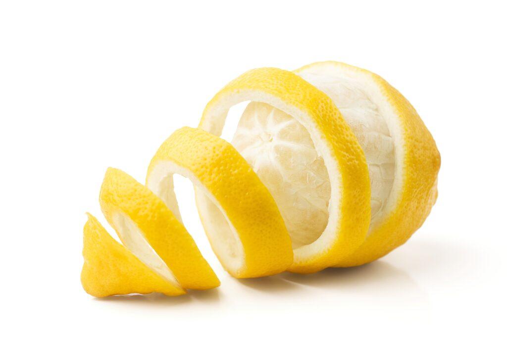 Geschälte Zitrone in Spiralen auf weißem Hintergrund, ideal für die Verwendung in Teisseire Sirup-Rezepten.