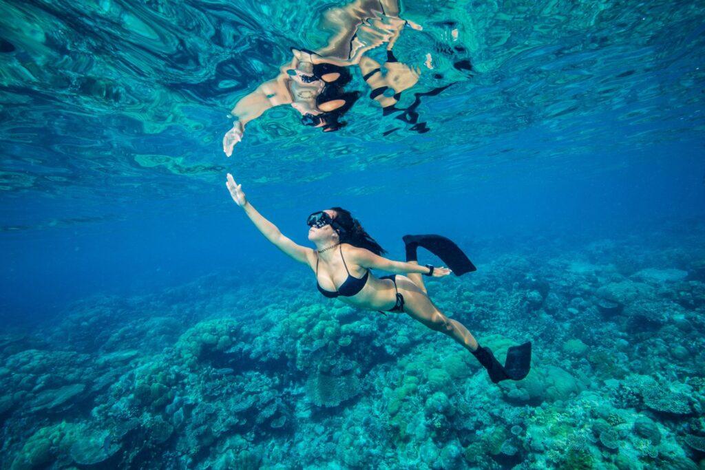 Frau schwimmt über Korallenriff im Meer